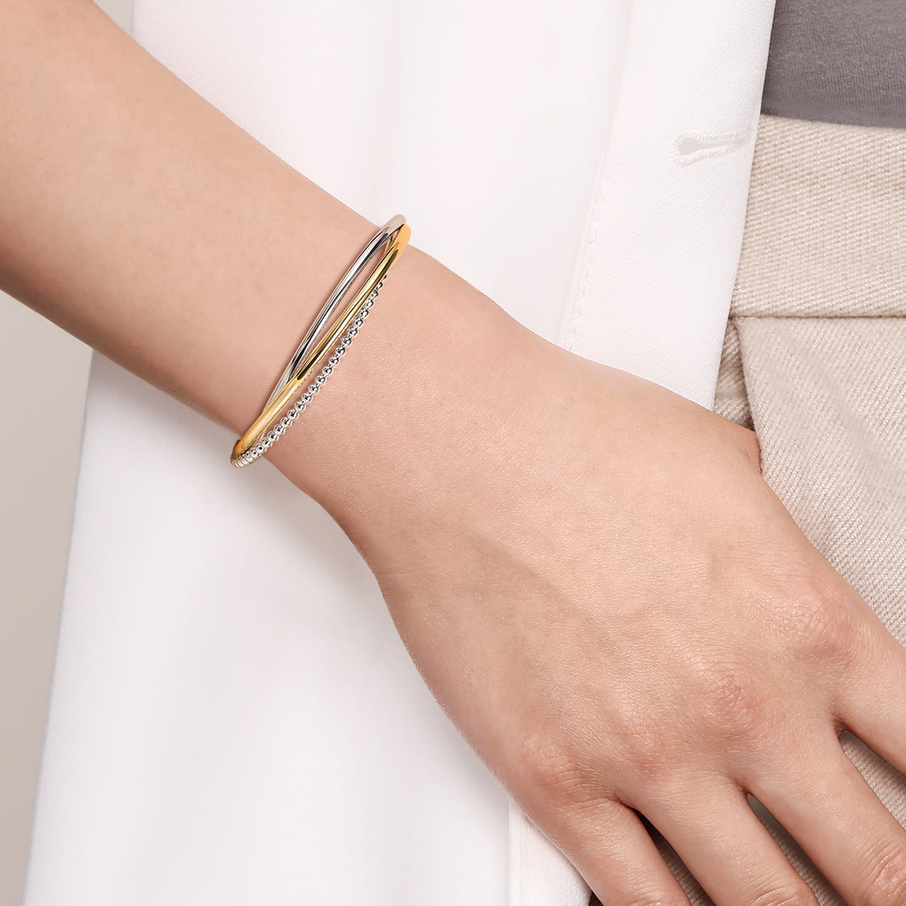 Gold bracelet on a person's wrist with a neutral background