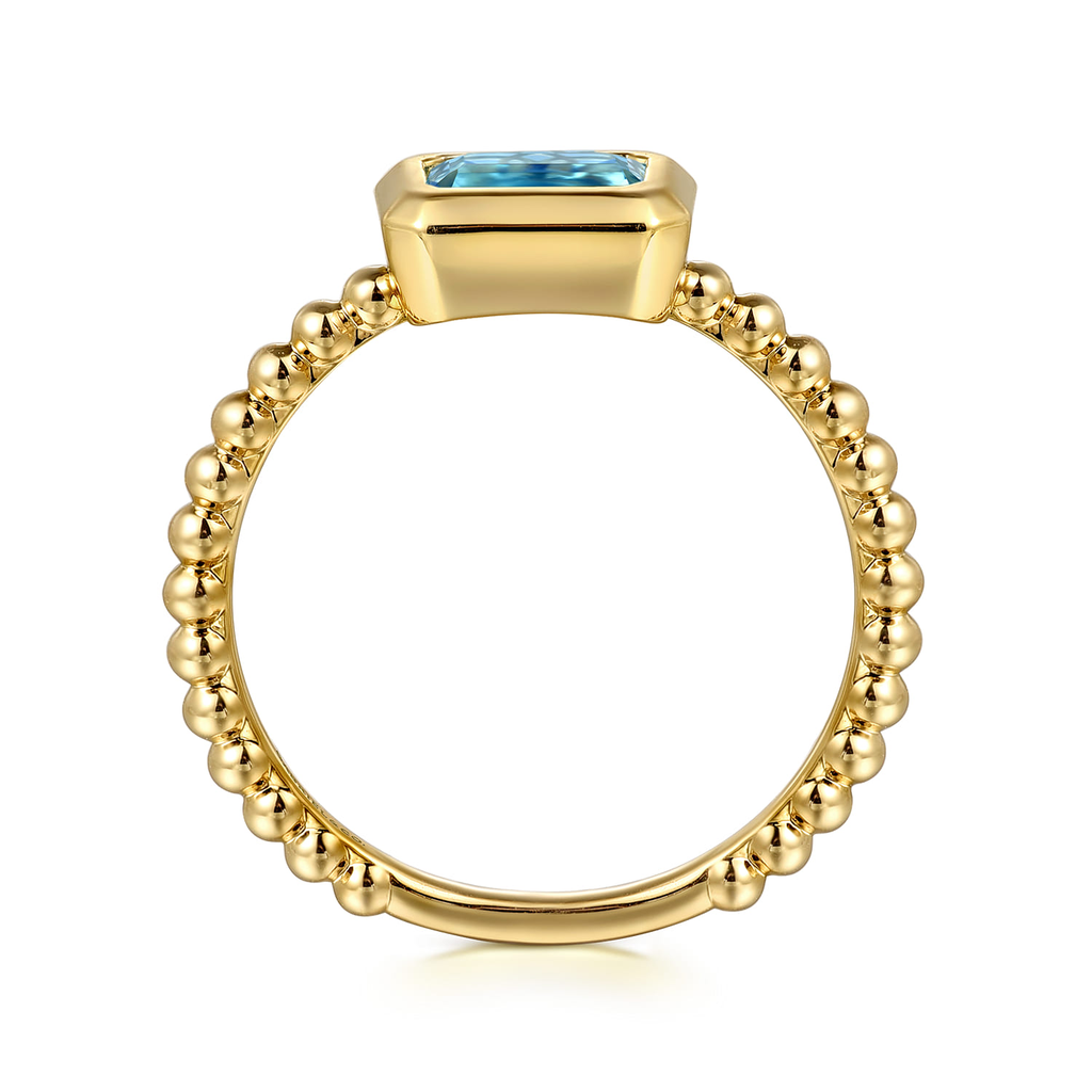 Gold ring with a blue gemstone on a white background