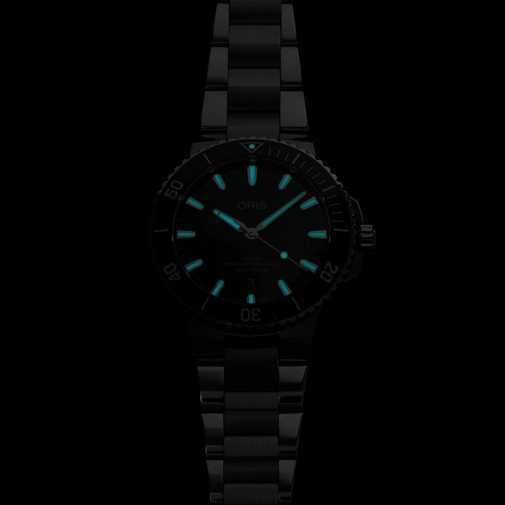 A black Oris watch with a matching black metal link bracelet, featuring bright luminescent turquoise hour markers and hands against a black dial, shown on a solid black background.