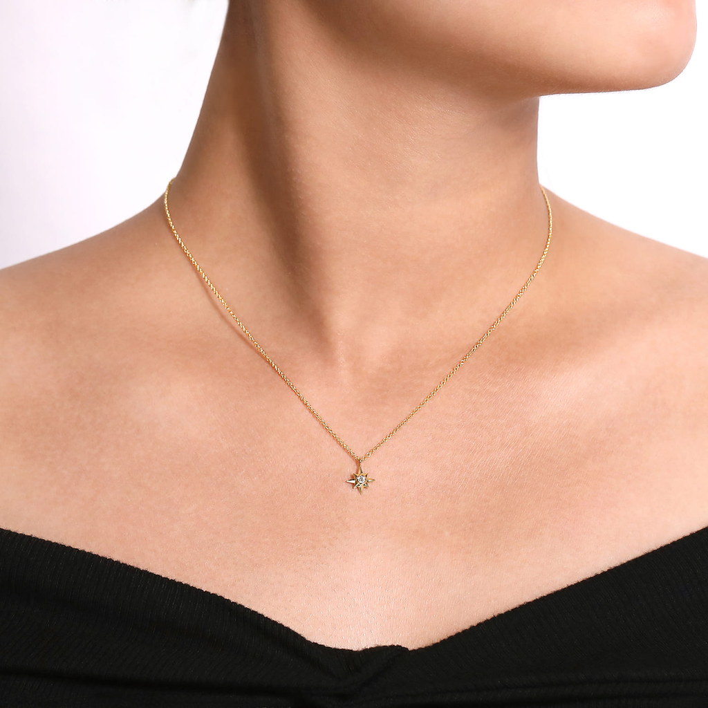 Gold necklace with a pendant on a model against a white background