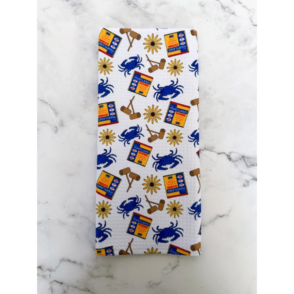 Folded towel with blue crab and yellow sunflower pattern on a marble surface