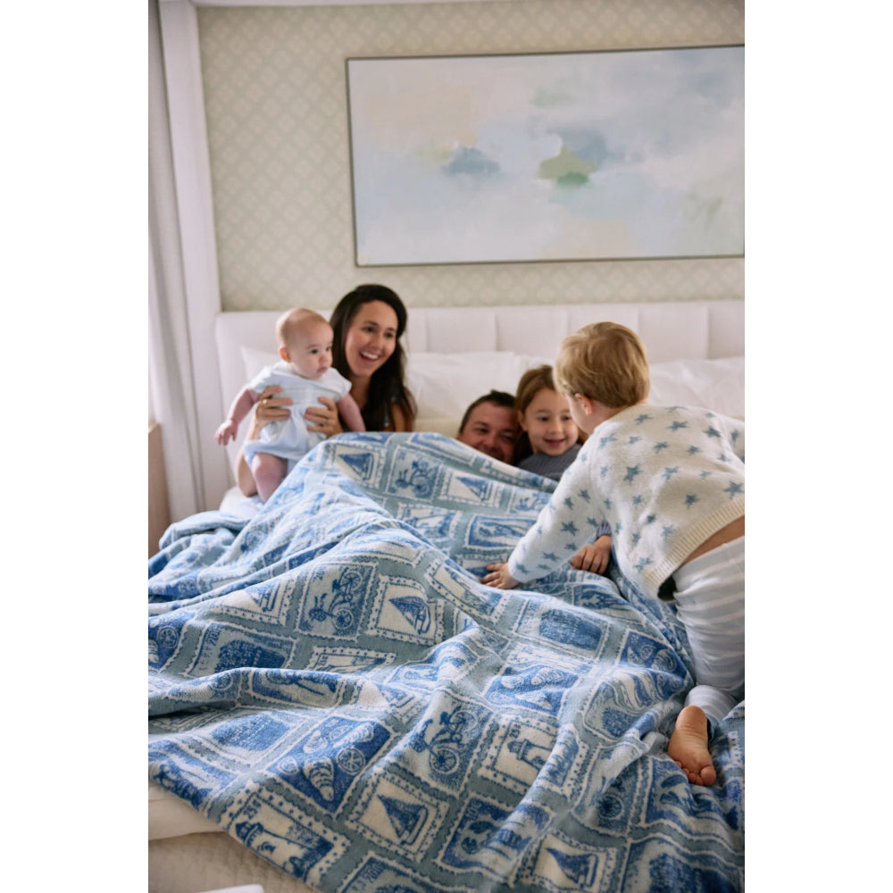 Family of five, including a baby, lying on a bed with a blue patterned blanket.