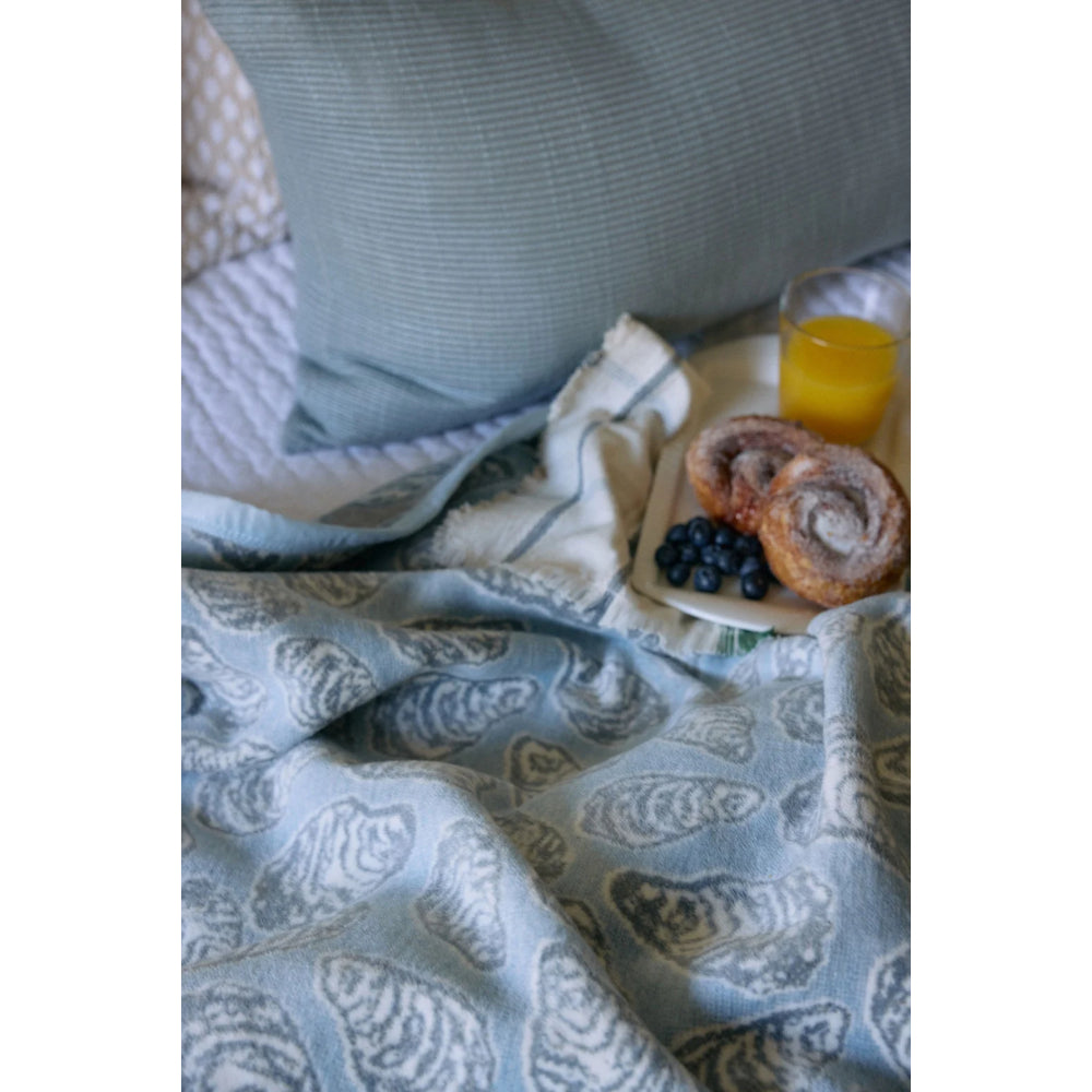 Patterned blanket on a bed with a small table holding food and juice.