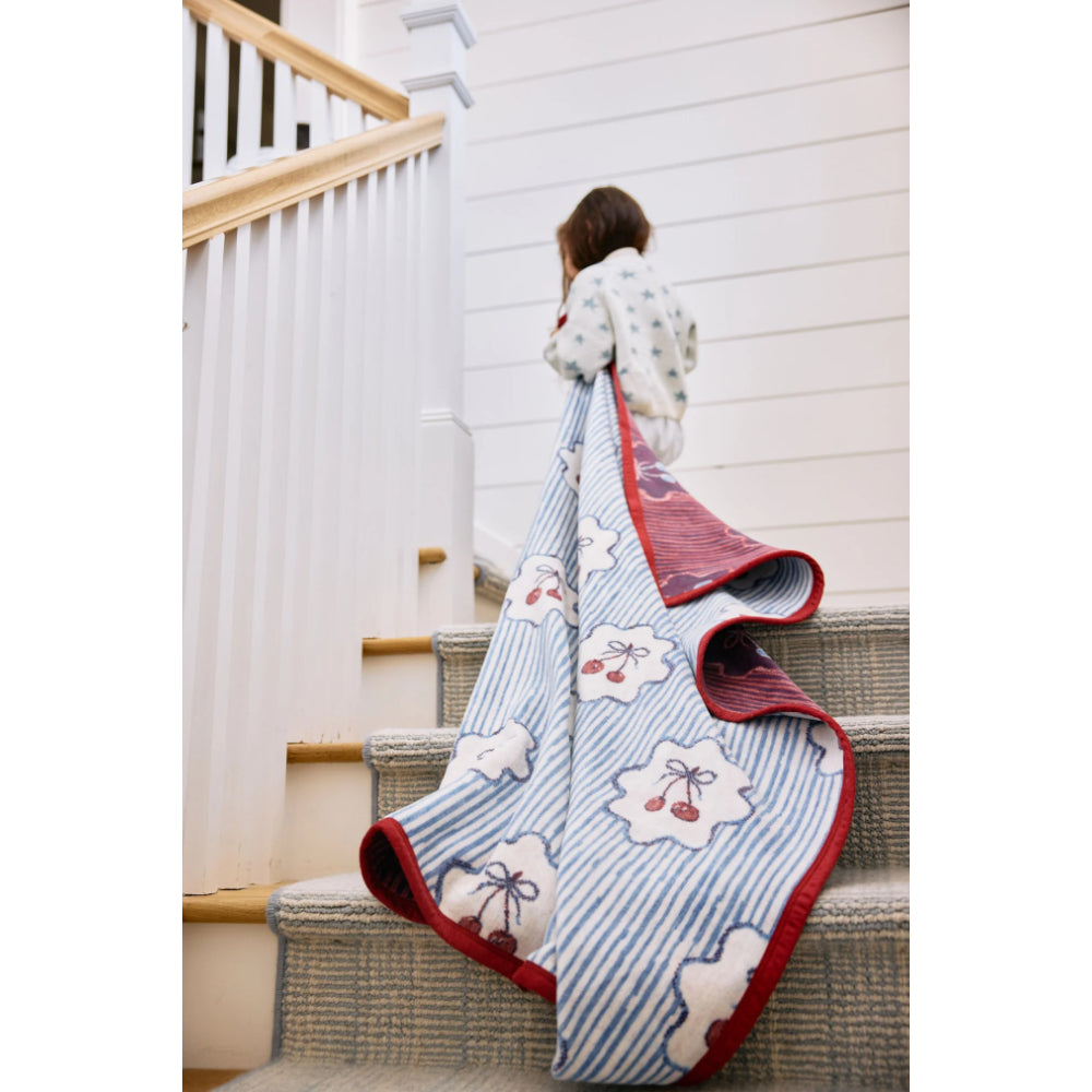 Person holding a floral and berry patterned blaket on a staircase