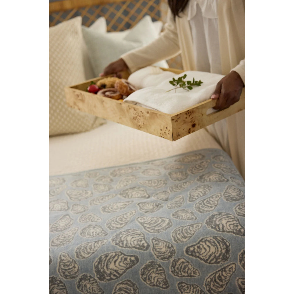 Person holding a tray with food on a bed with a patterned blanket