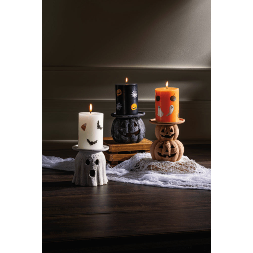 Halloween-themed candles on decorative stands with a dark background