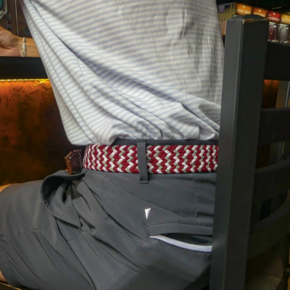 Person wearing a striped shirt, gray shorts, and a red and white belt sitting on a chair.