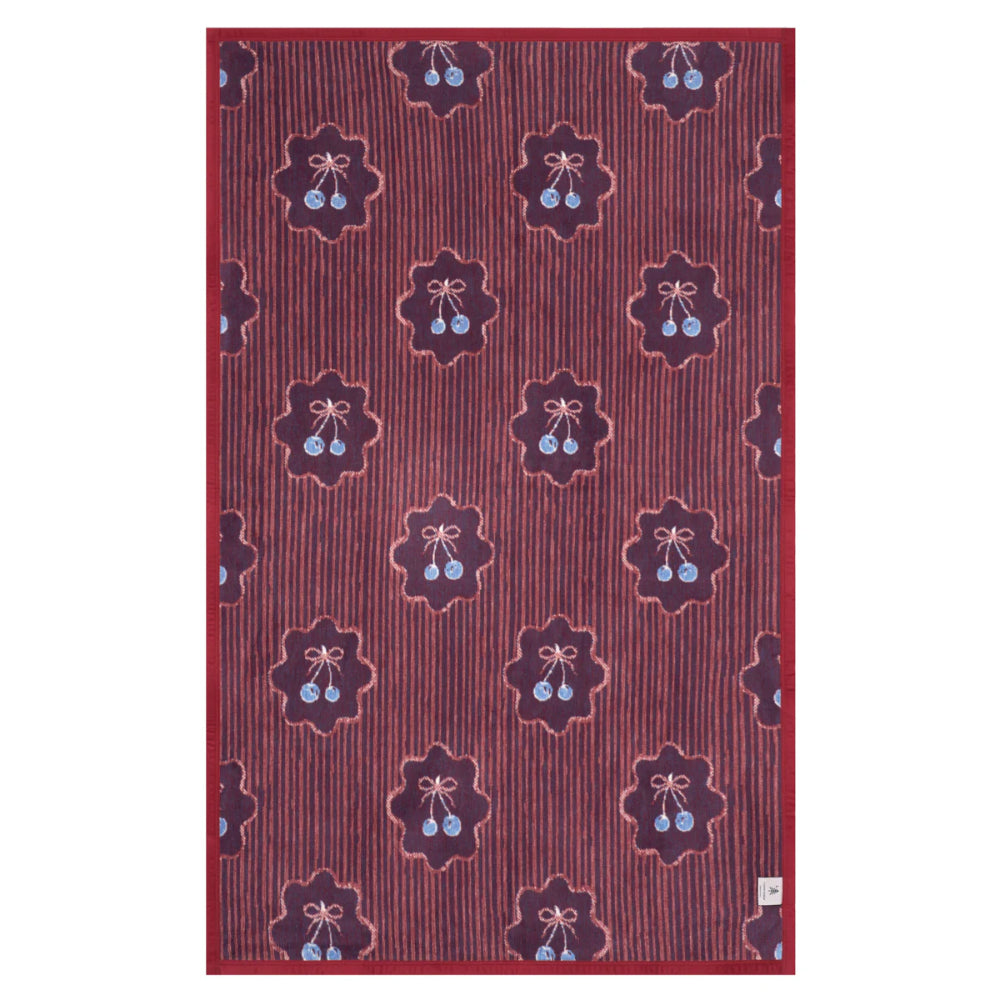 Red patterned blanket with floral and berry designs on a white background