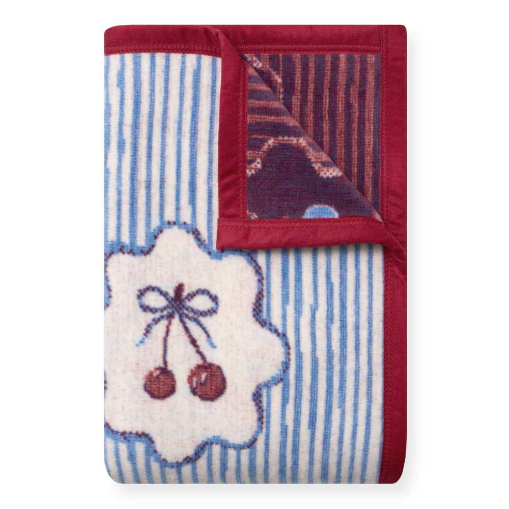Folded blanket with floral and berry design and red border on a white background