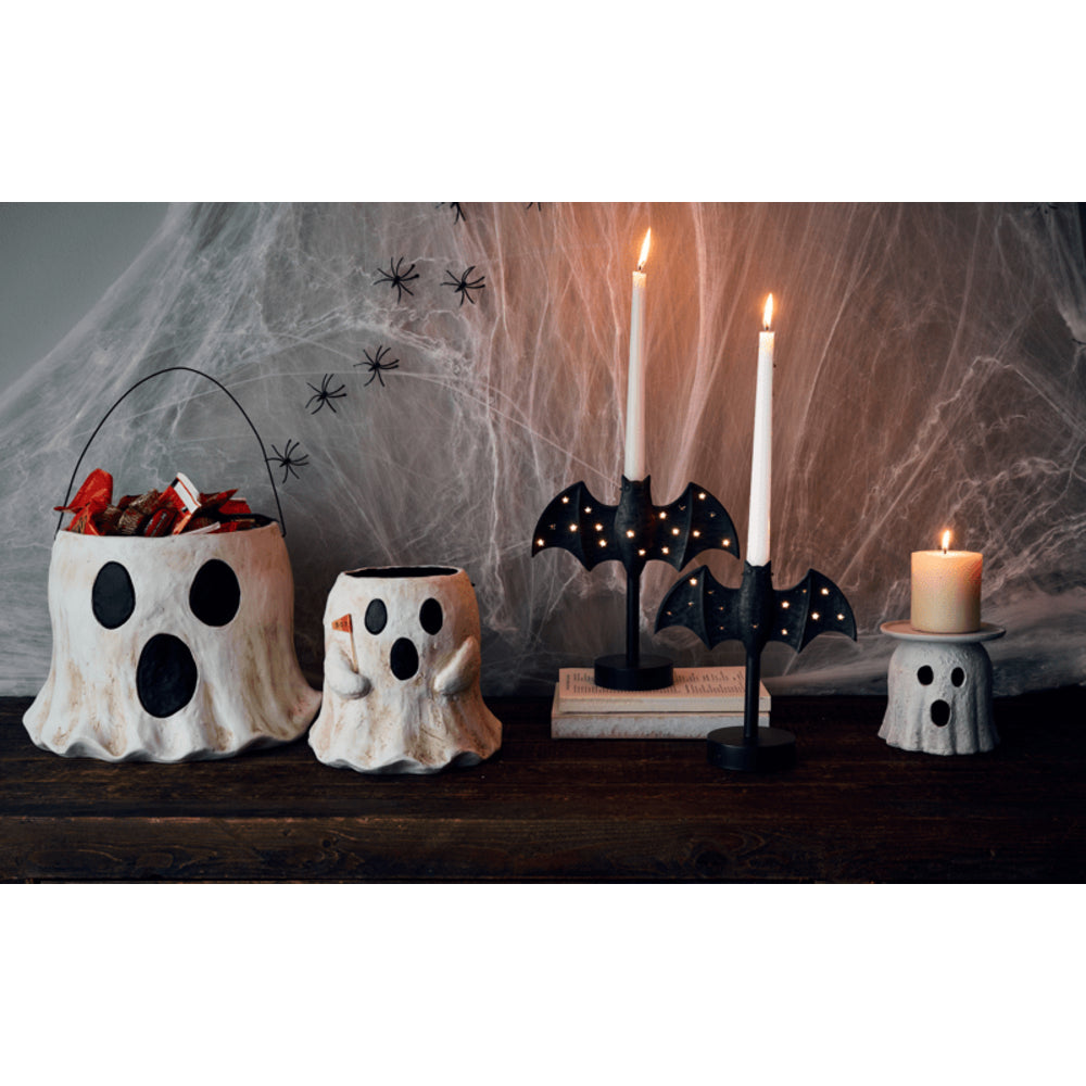 Halloween-themed decor with ghost-shaped buckets, candles, and a bat-shaped candle holder.
