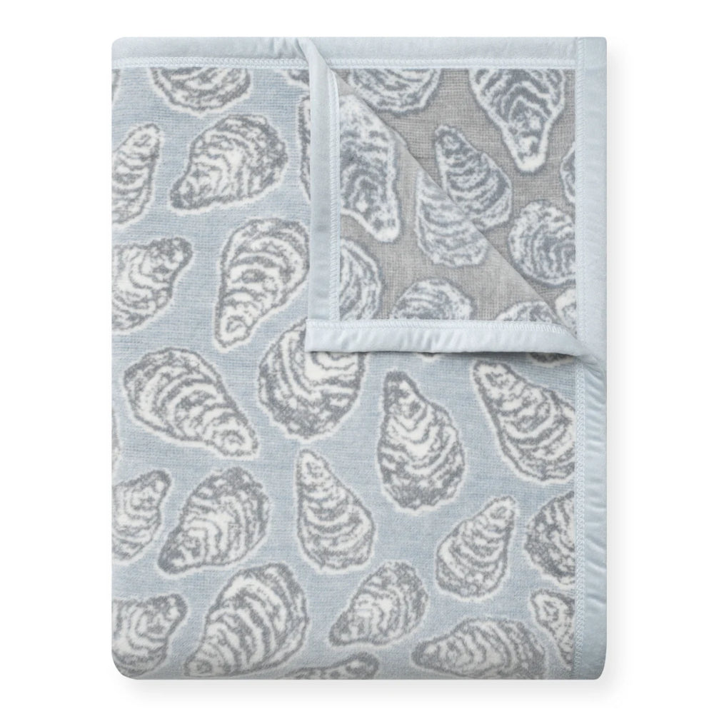 Folded blanket with oyster shell pattern on a light blue background