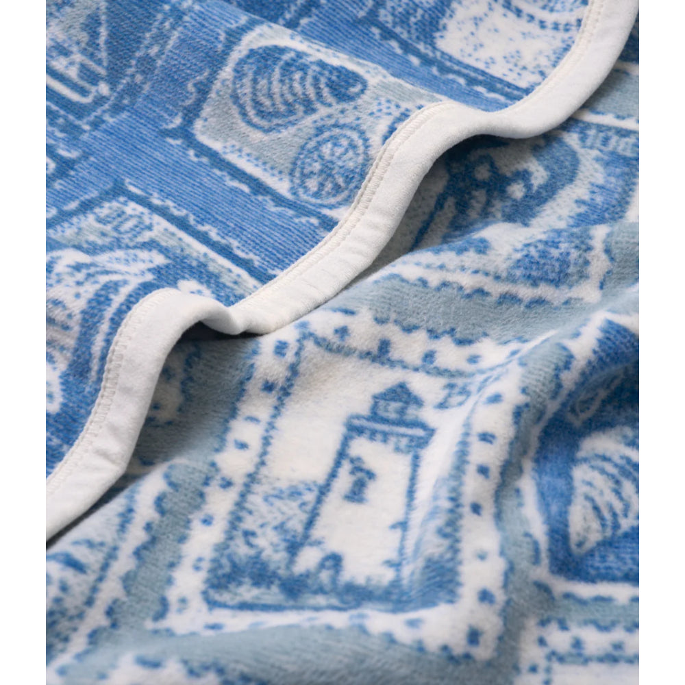 Close-up of a blue and white blanket fabric with a lighthouse design.