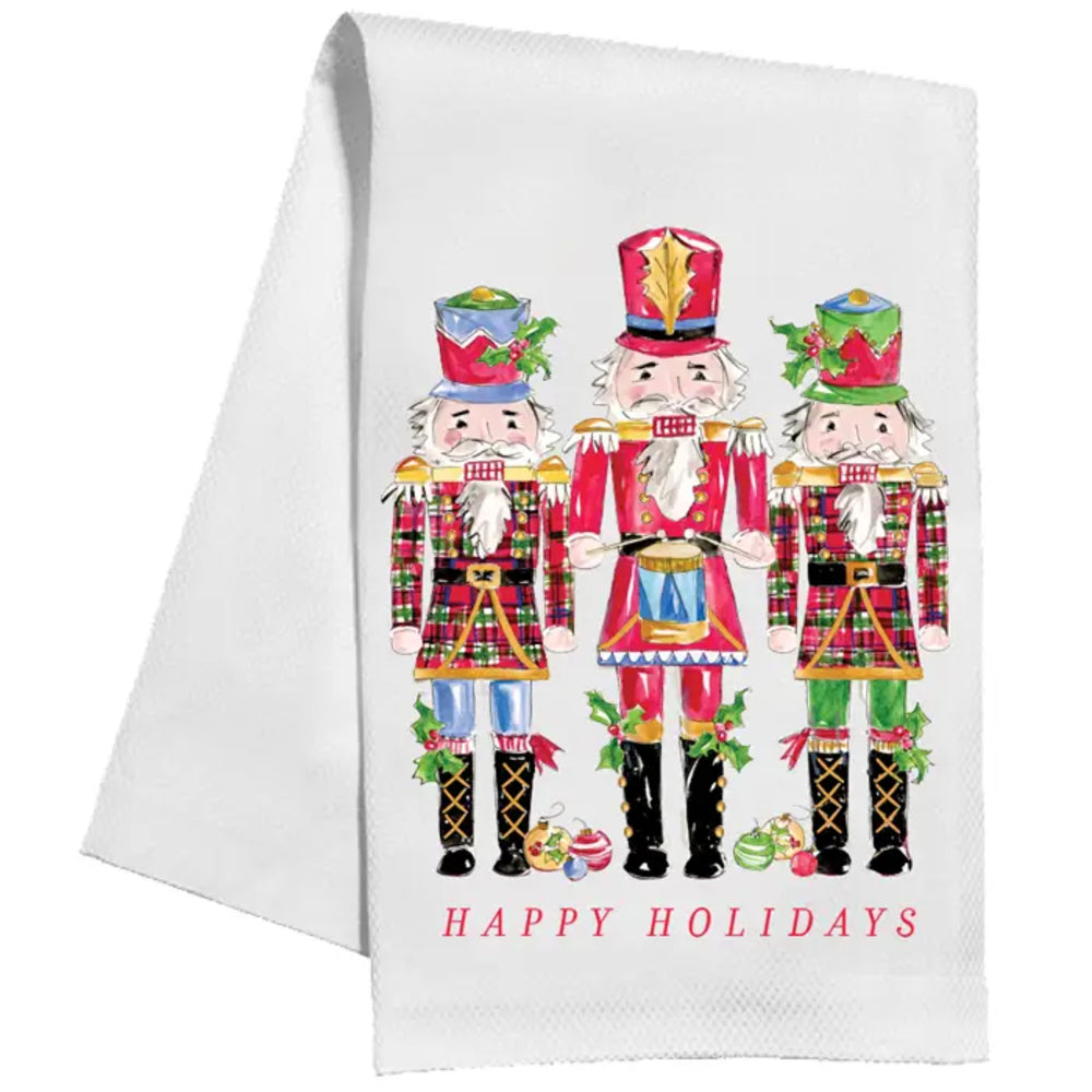 A white kitchen towel featuring a colorful illustration of three nutcracker figures and the text 'HAPPY HOLIDAYS' printed on it, shown against a plain white background.