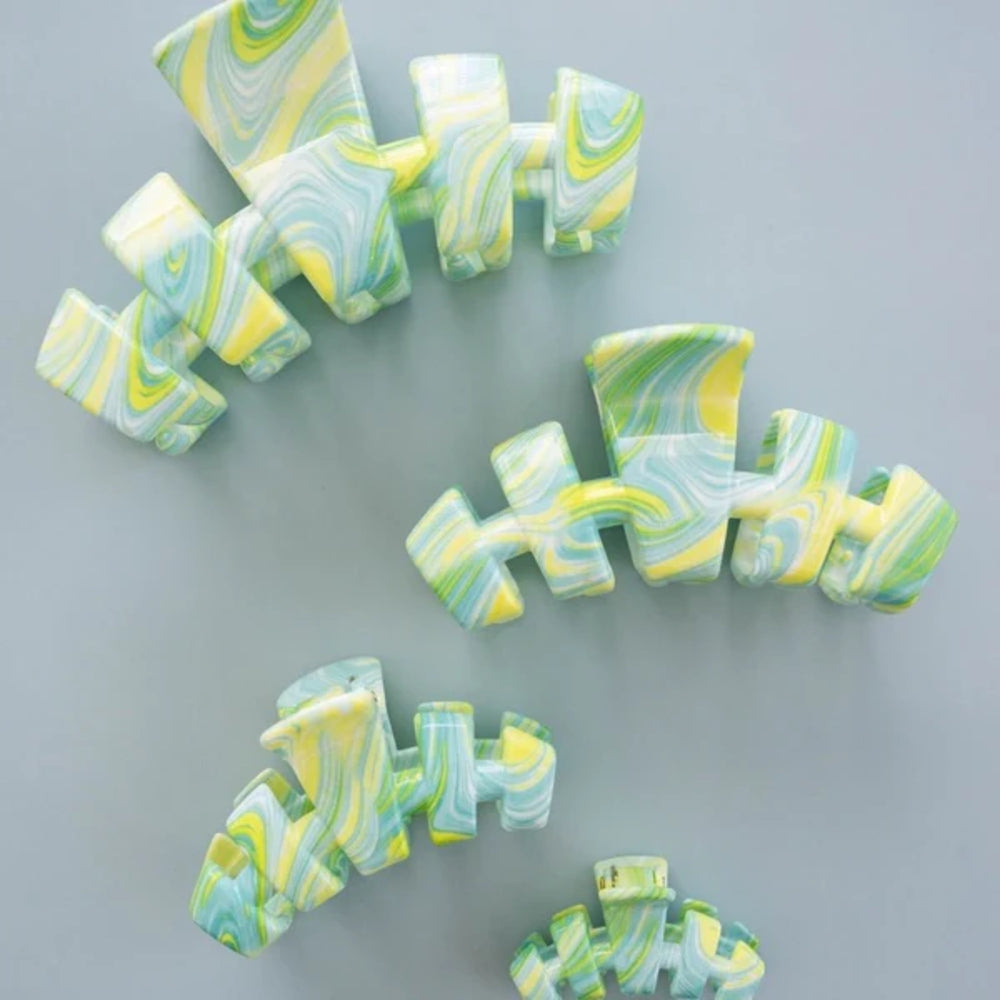 Marbled green and yellow hair clips on a gray background