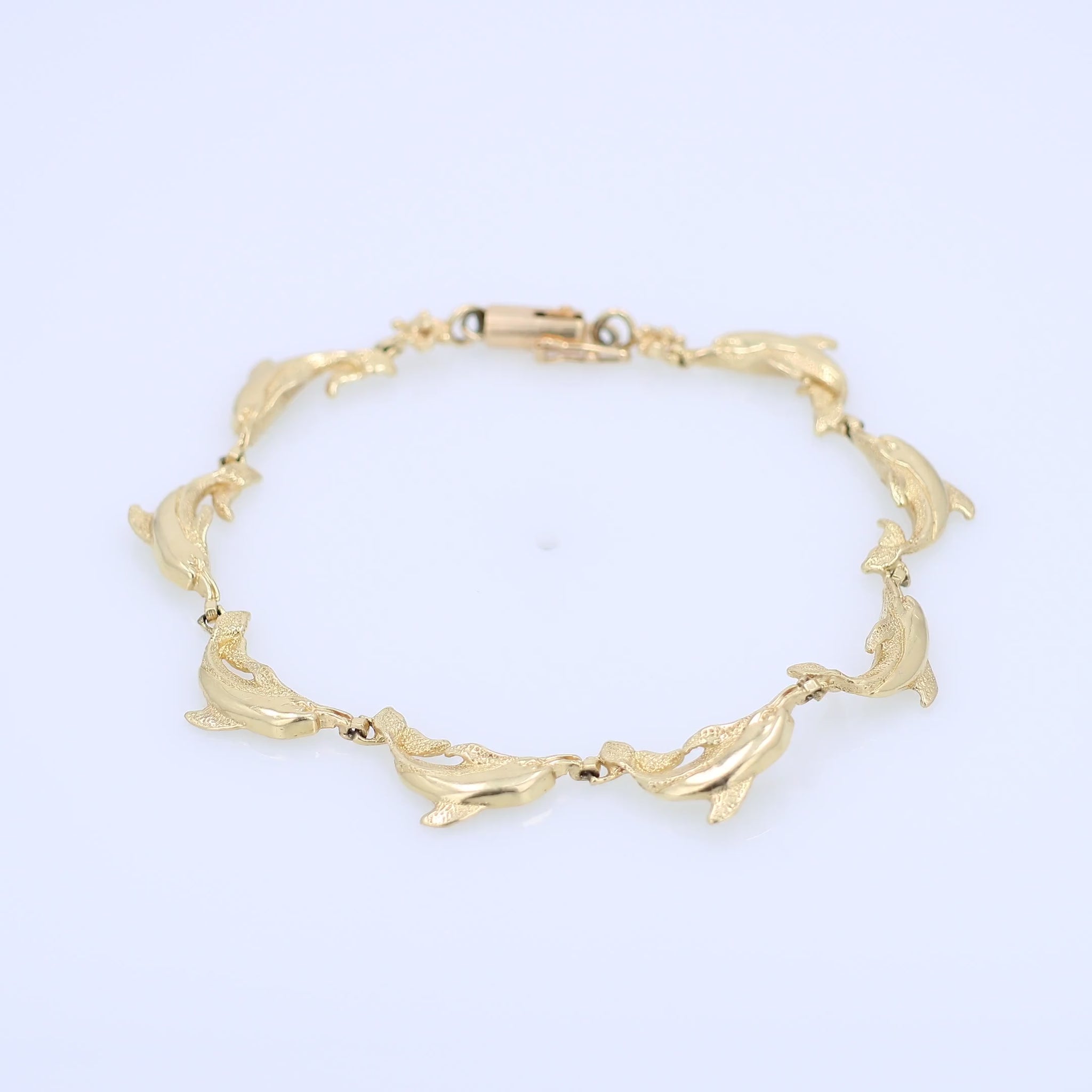 Yellow gold dolphin link bracelet on a white background