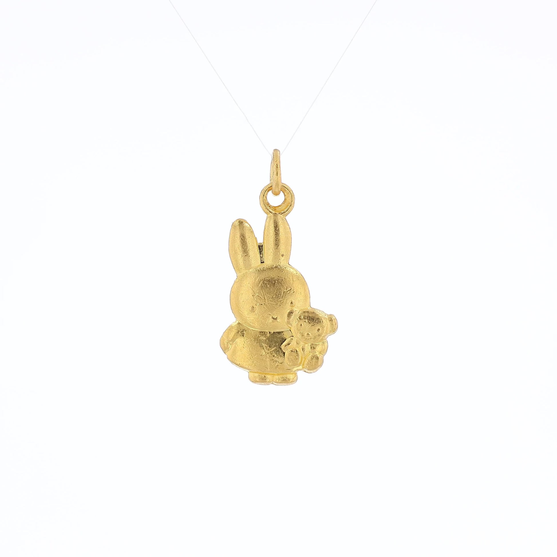 Yellow gold pendant depicting Miffy the Rabbit holding a stuffed animal bear on a white background