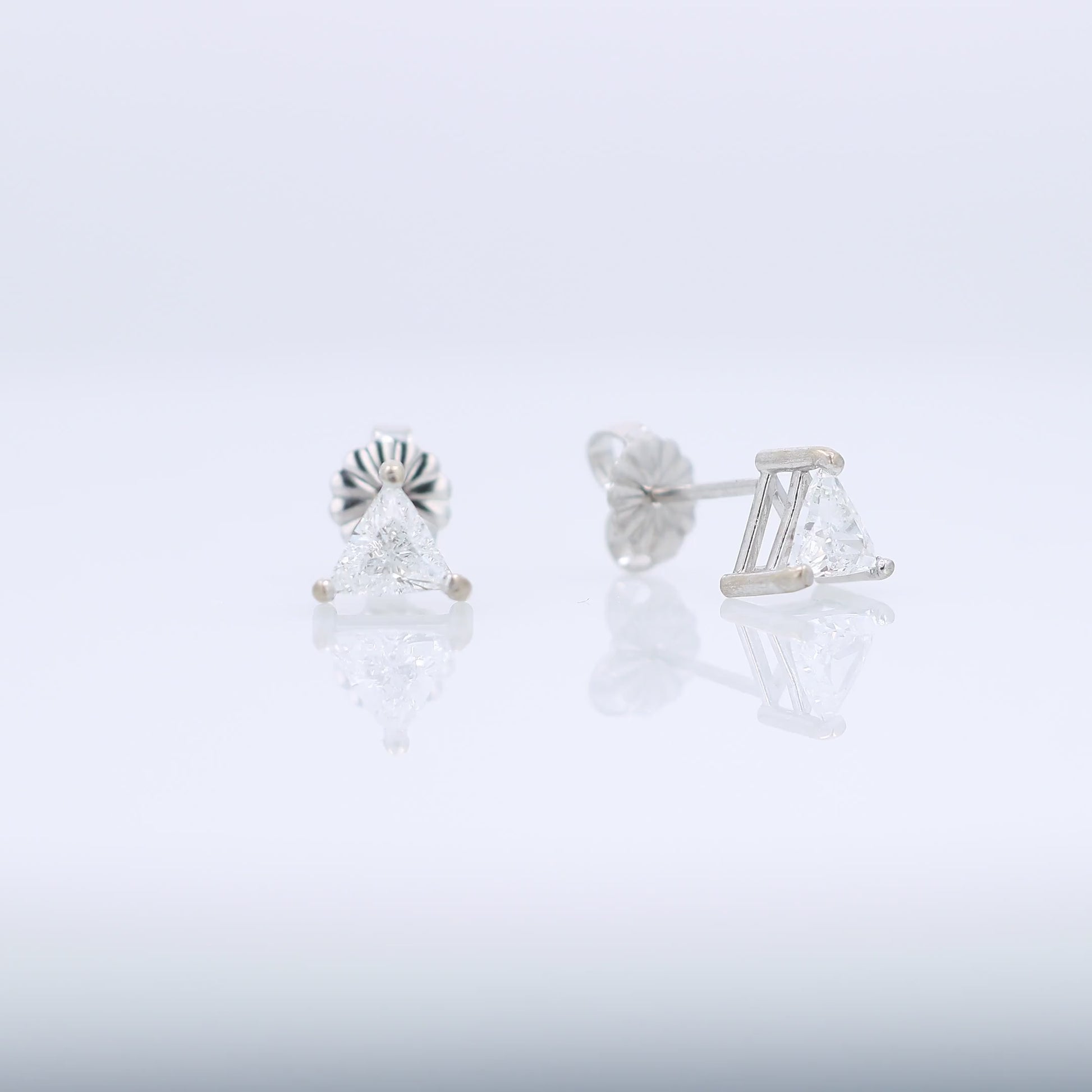 White gold trillion cut diamond stud earrings totaling 0.76 carats on a white background