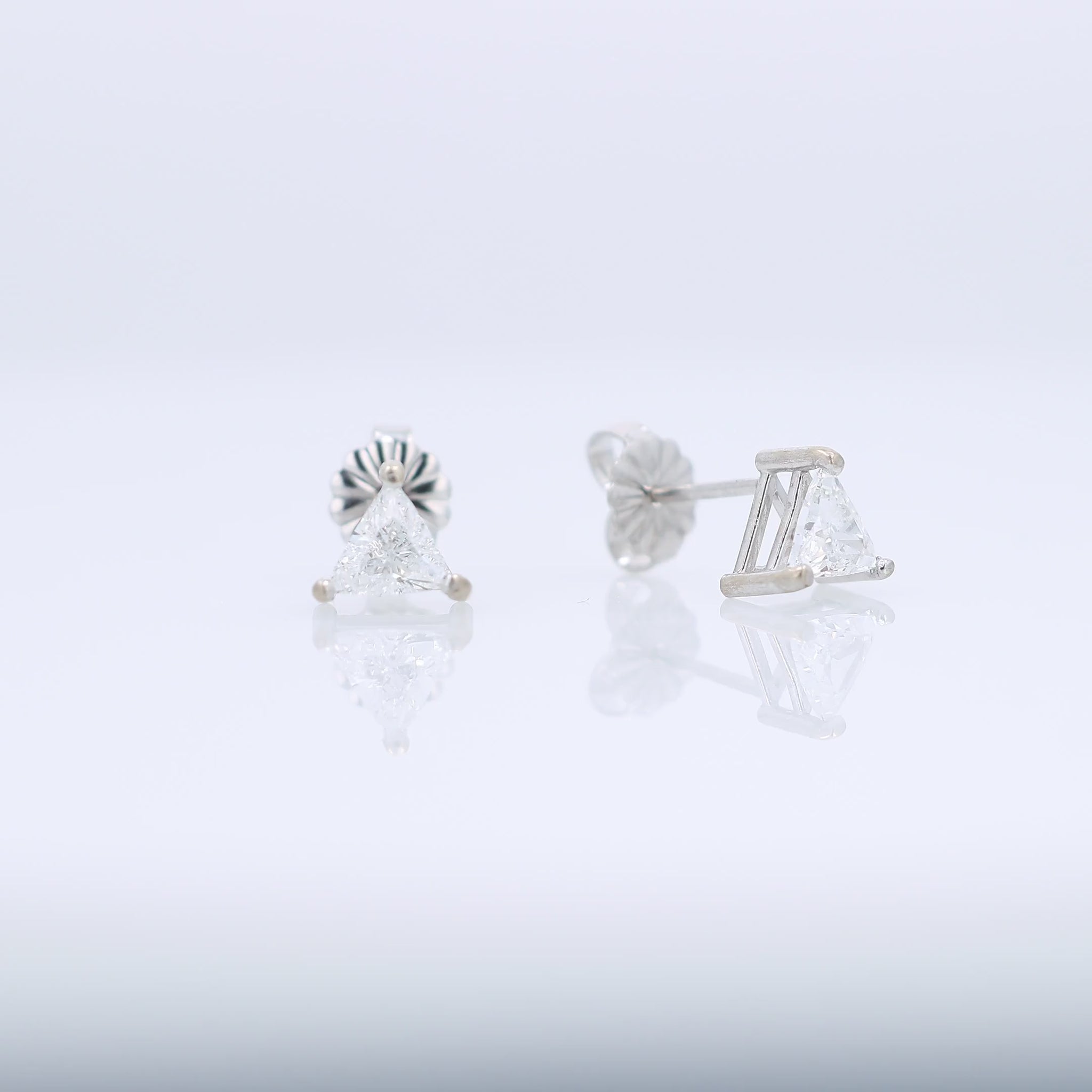 White gold trillion cut diamond stud earrings totaling 0.76 carats on a white background