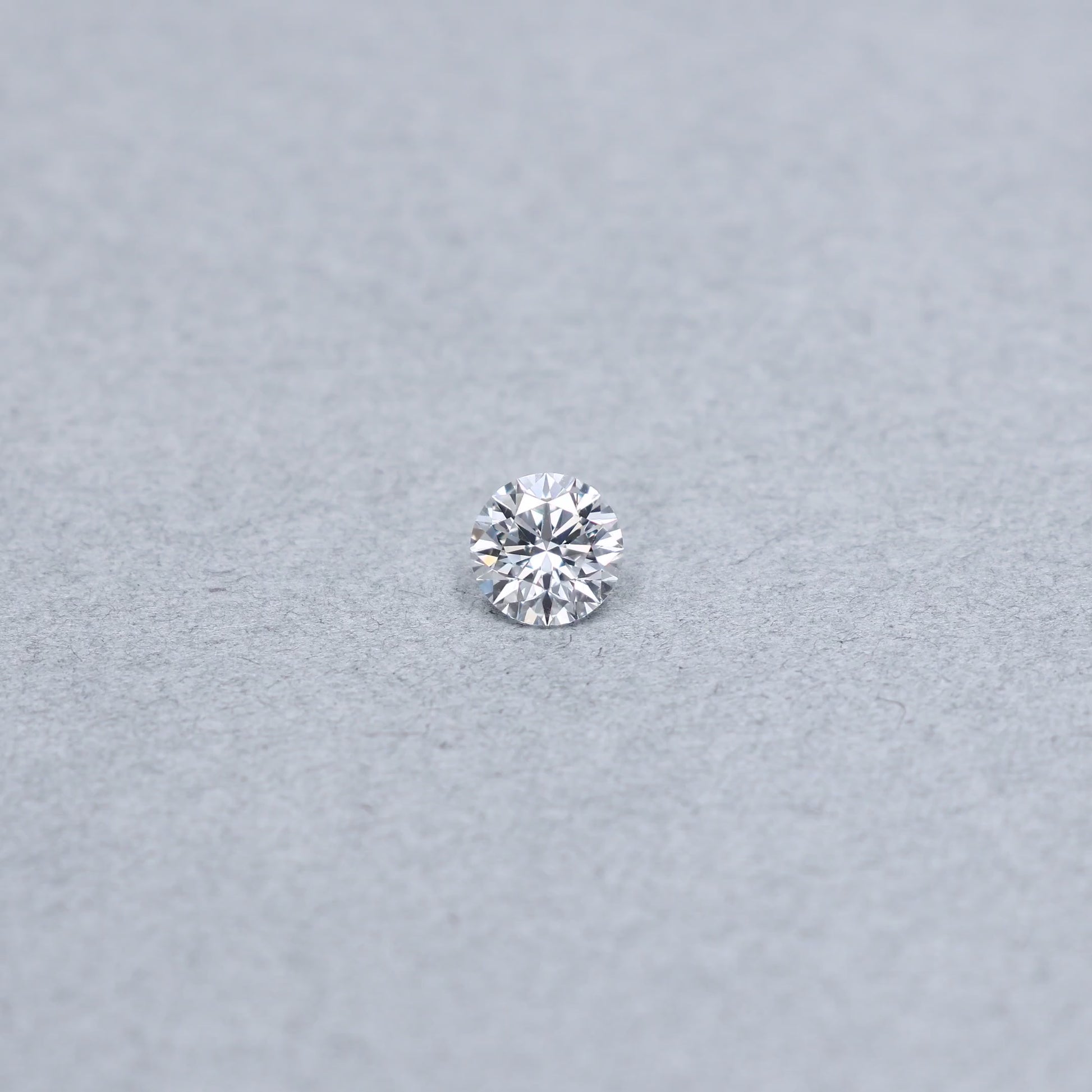 Round .90 carat triple excellent GIA certified diamond graded EVVS1 on a grey background