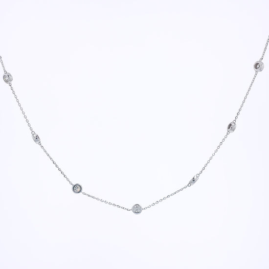 A delicate white gold chain necklace featuring multiple small, bezel-set round diamond stations displayed against a solid white background.