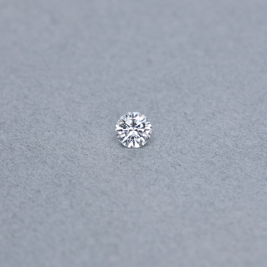 Round .79 carat diamond graded FSI1 on a grey background