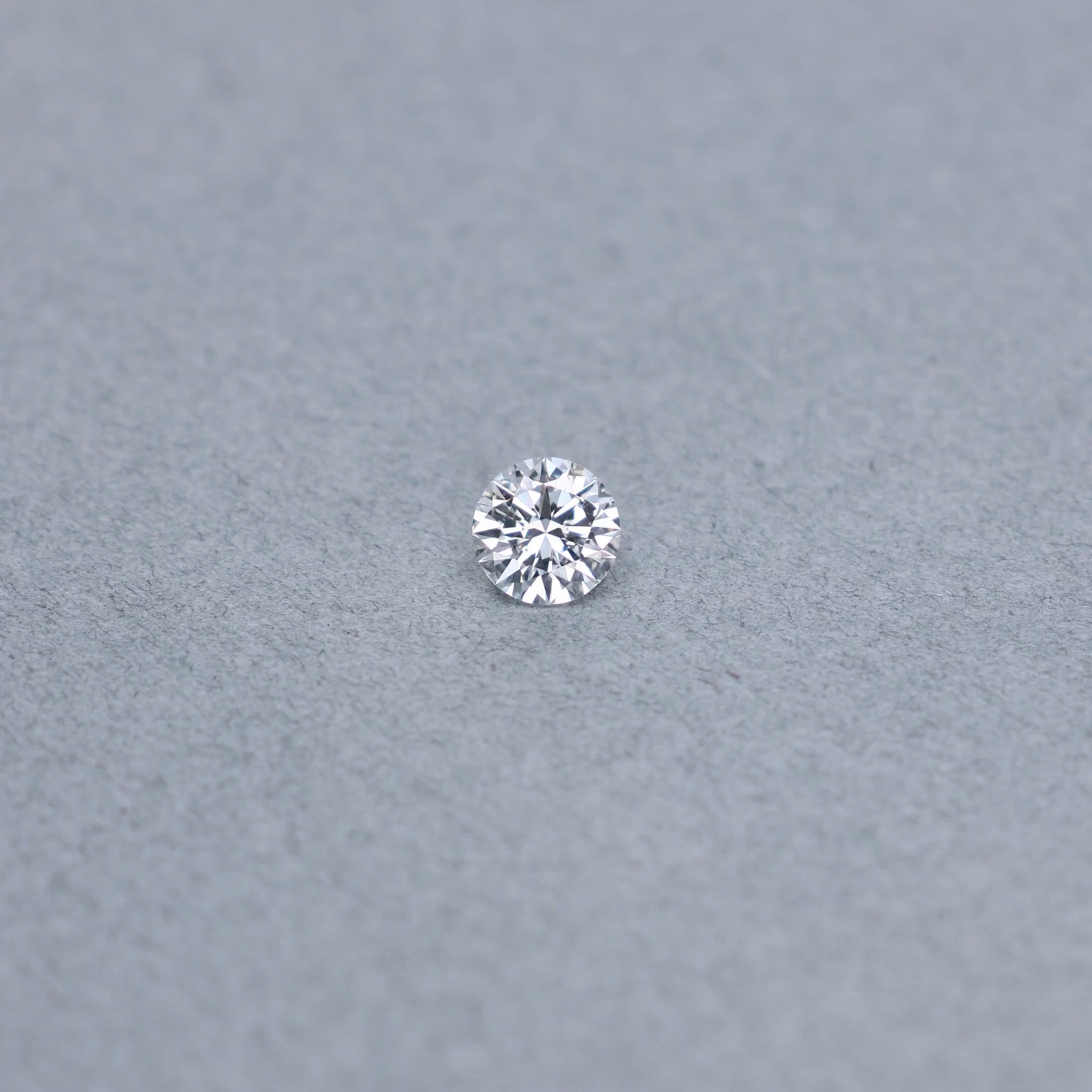 Round .79 carat diamond graded FSI1 on a grey background