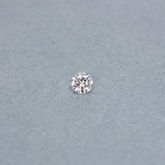 Round .70 carat diamond graded ISI2 on a grey background