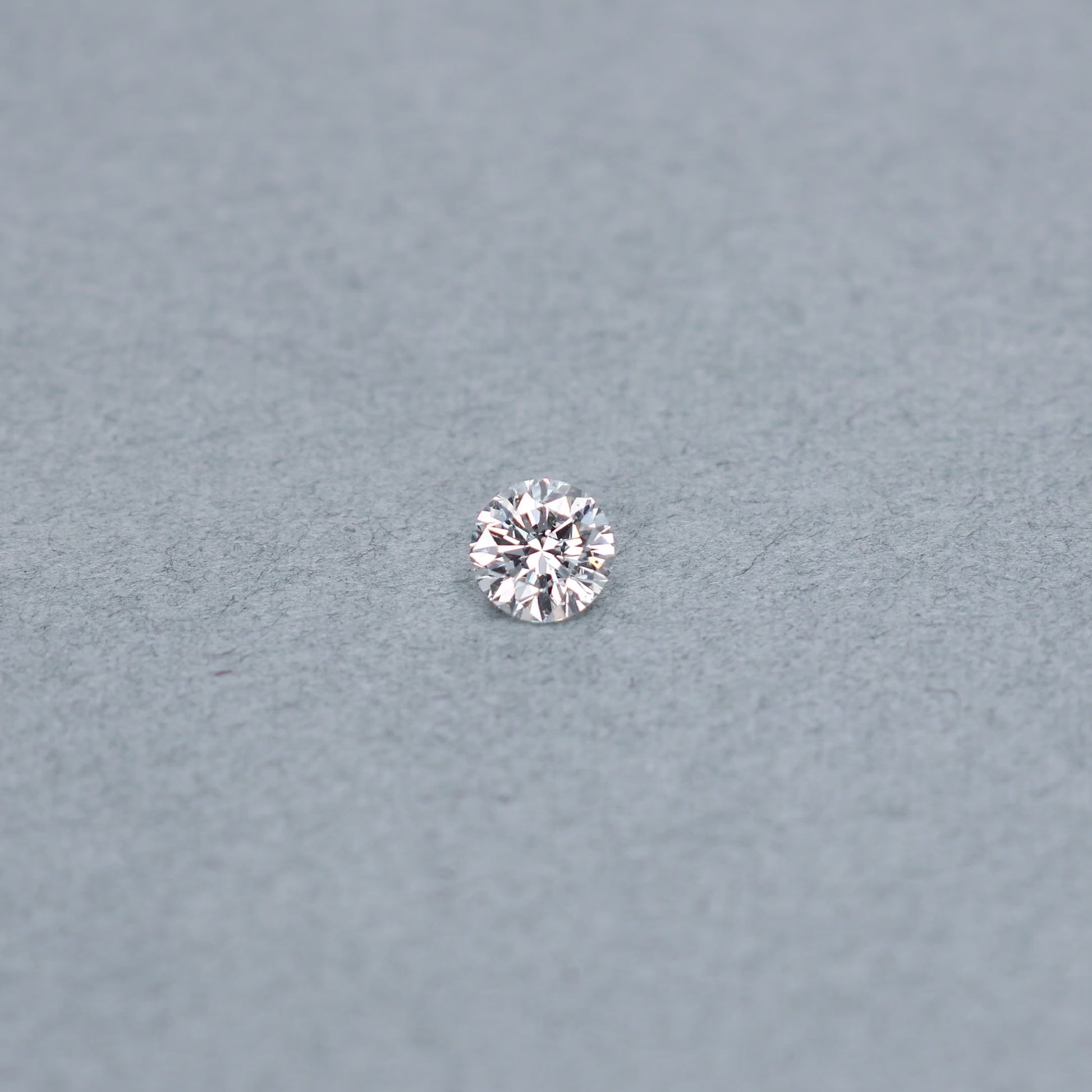 Round .70 carat diamond graded ISI2 on a grey background
