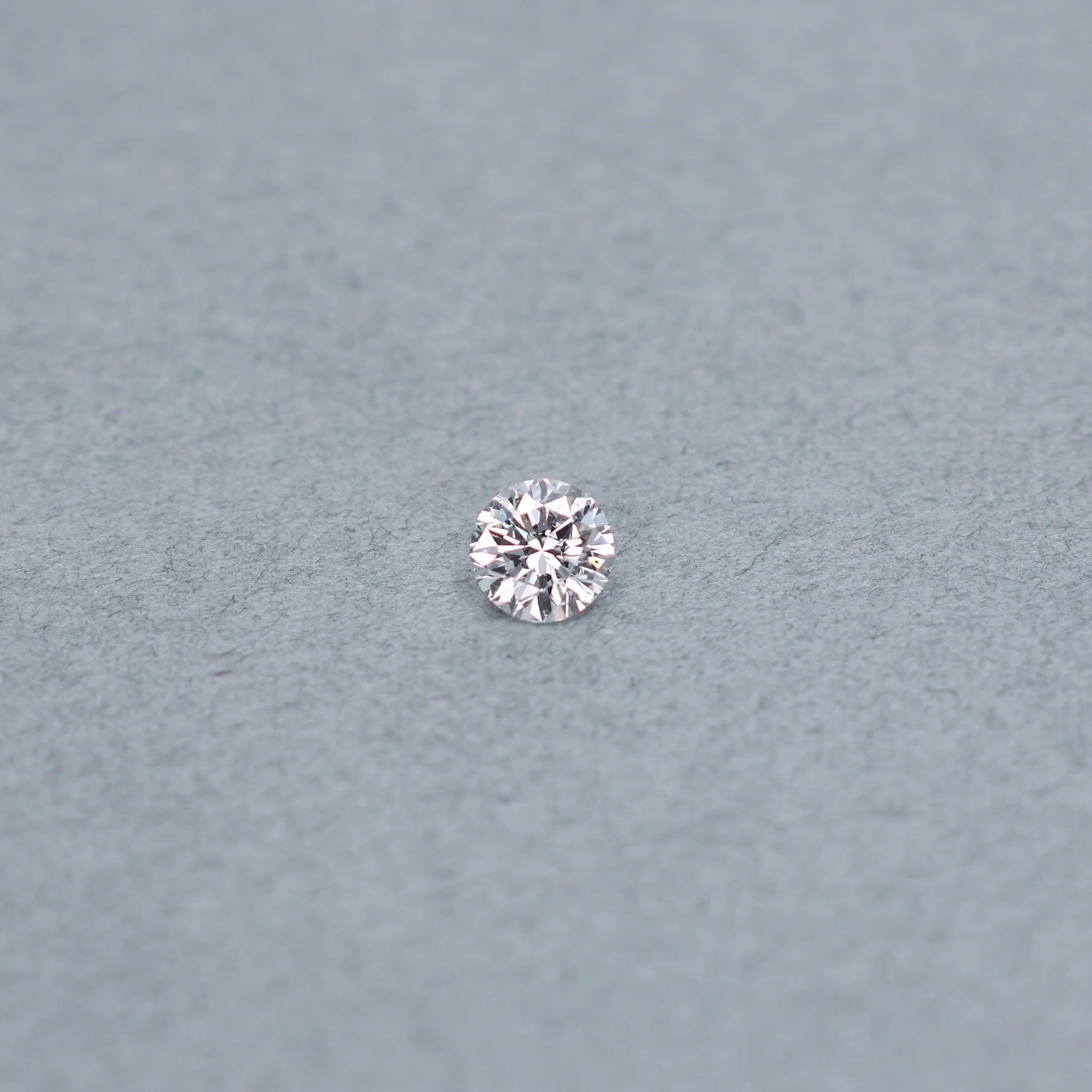 Round .70 carat diamond graded ISI2 on a grey background