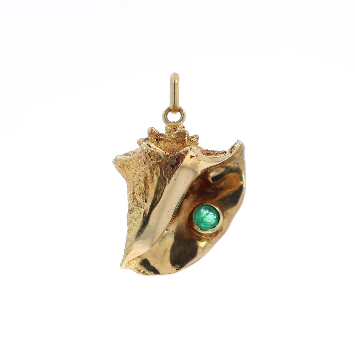 A gold conch shell pendant featuring a small round emerald inset, shown on a clean white background
