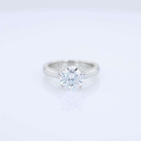 Platinum diamond solitaire engagement ring with diamond accents and a round cubic zirconia center on a white background