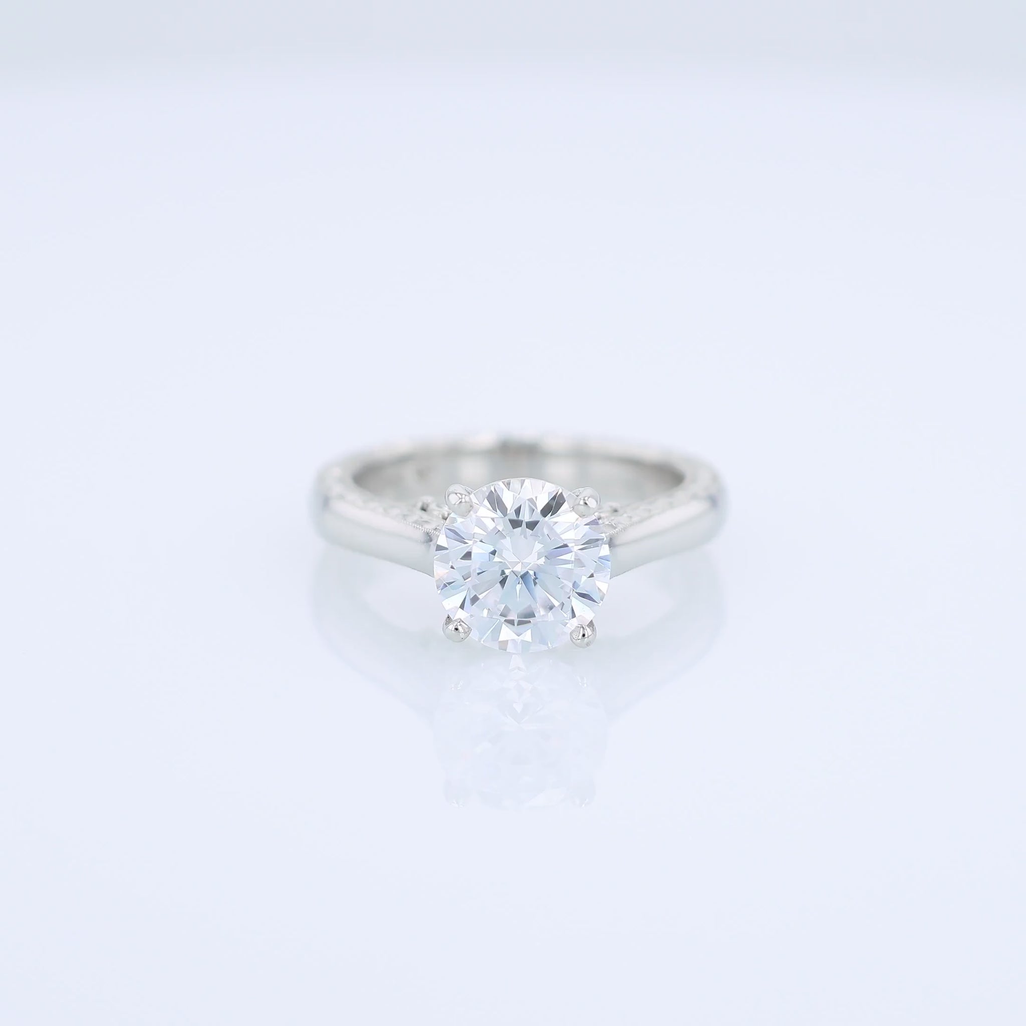Platinum diamond solitaire engagement ring with diamond accents and a round cubic zirconia center on a white background