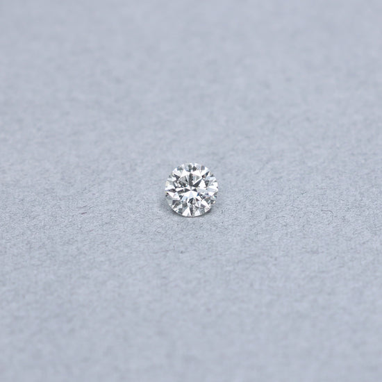 Round .85 carat diamond graded KI1 on a grey background