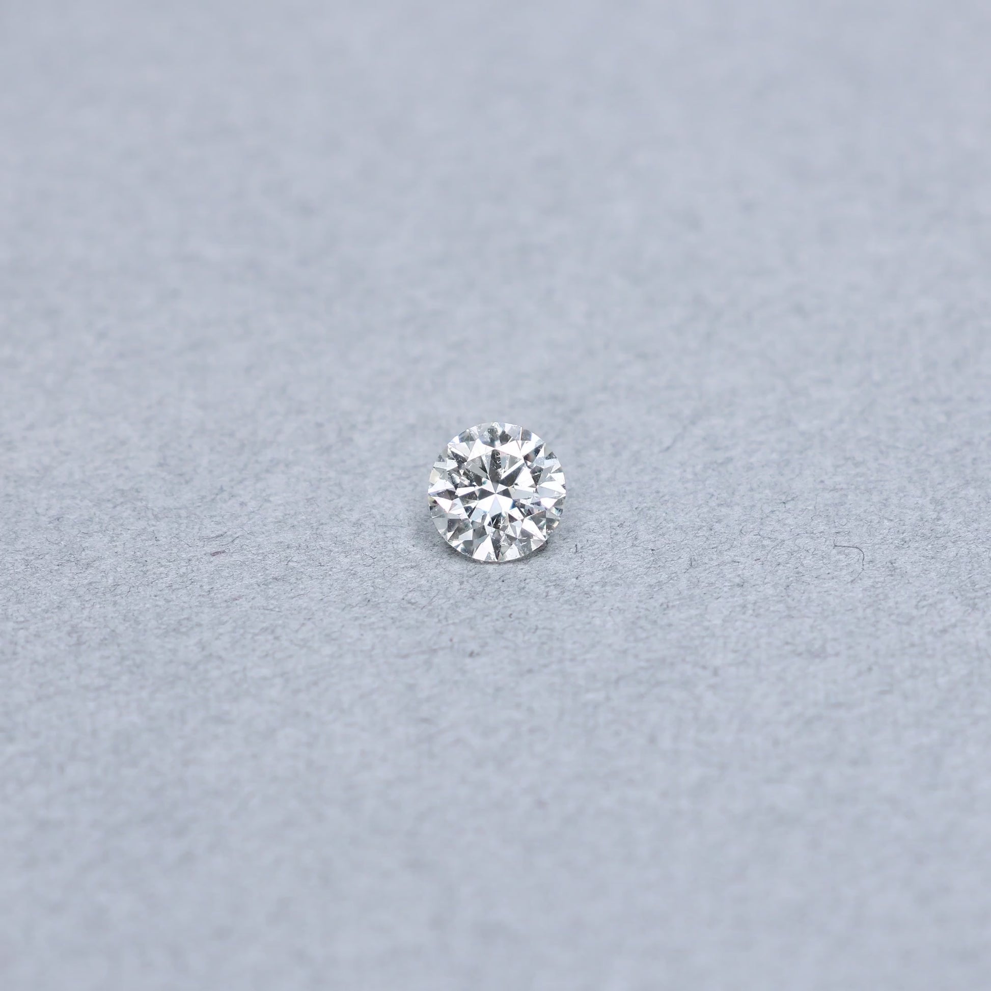 Round .85 carat diamond graded KI1 on a grey background
