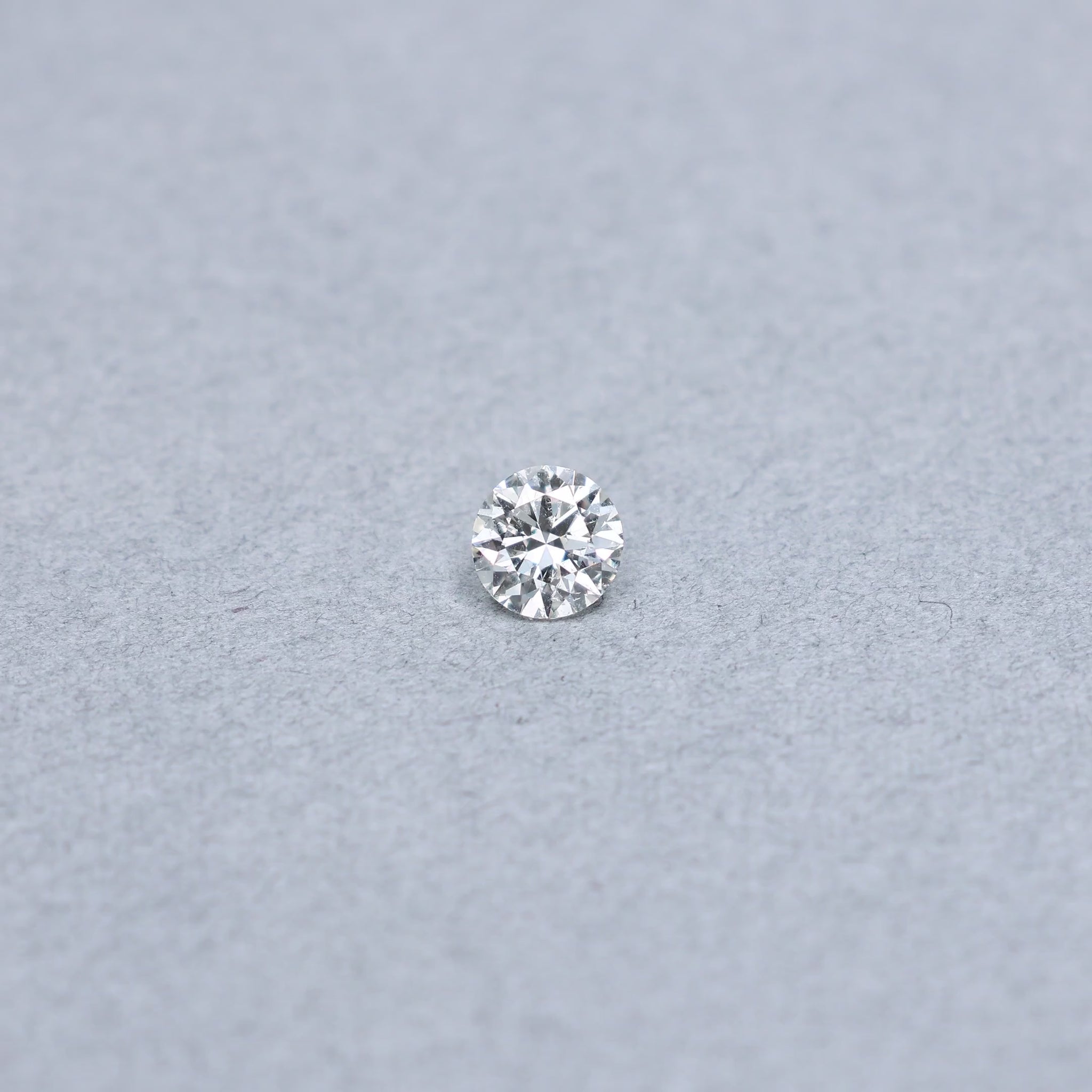 Round .85 carat diamond graded KI1 on a grey background