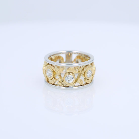 Two-tone gold open work floral band with diamond bezels on a white background