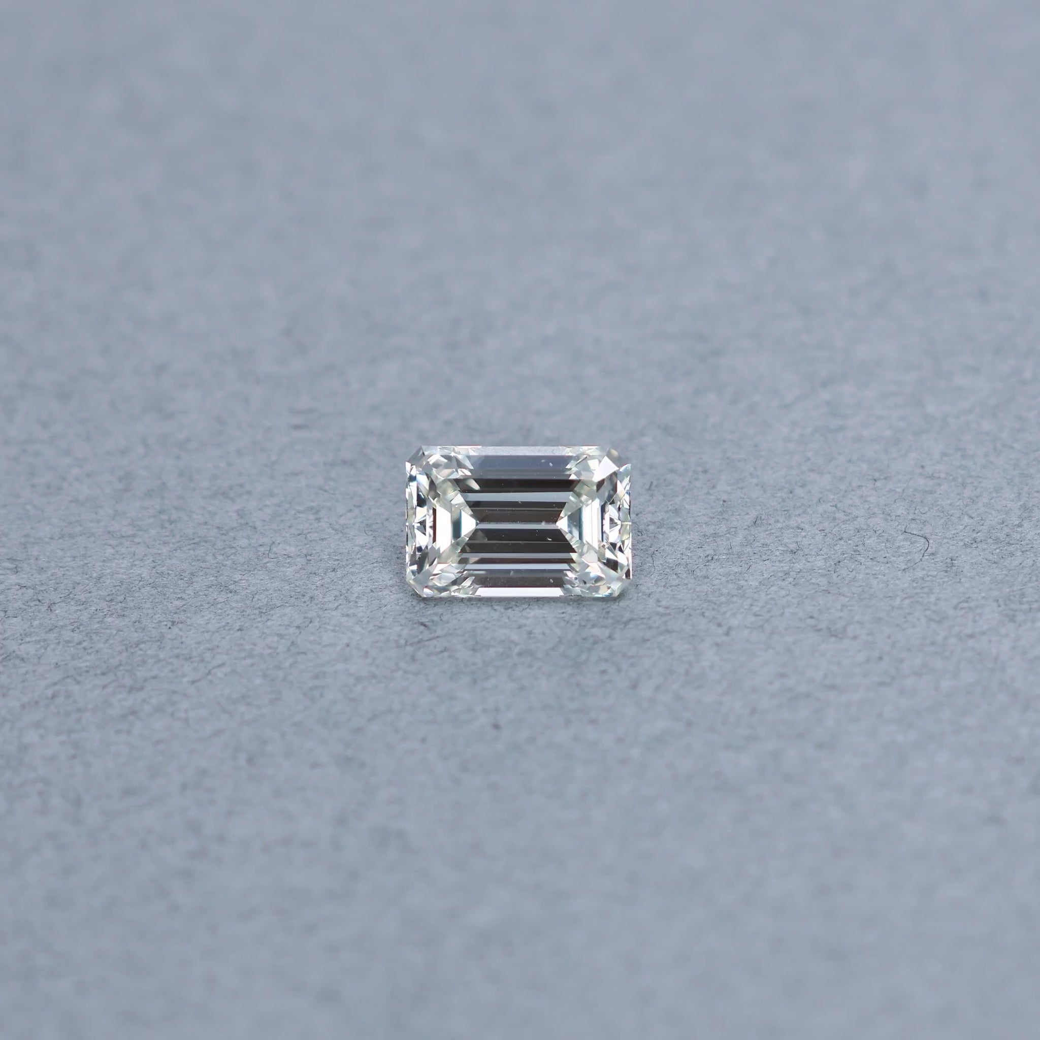 Emerald cut 2.45 carat GIA certified diamond graded JVS2 on a grey background