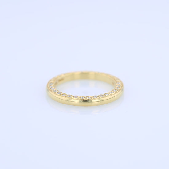 Yellow gold wedding band with diamond accents on a white background