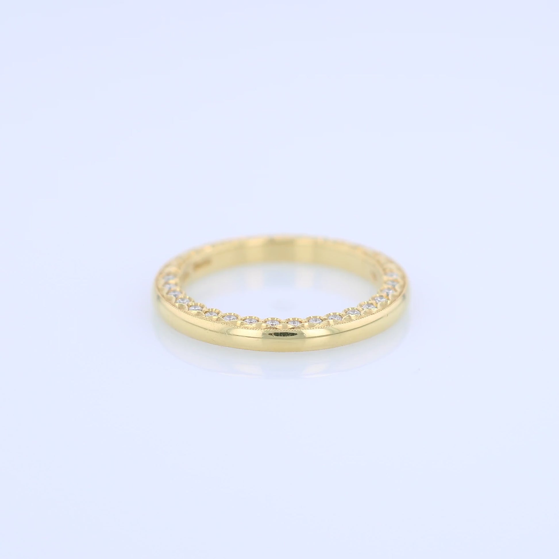 Yellow gold wedding band with diamond accents on a white background