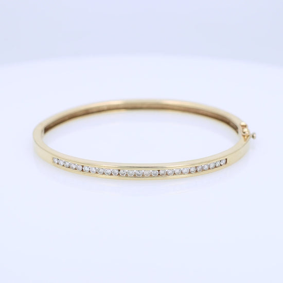 Yellow gold channel set diamond bangle bracelet on a white background