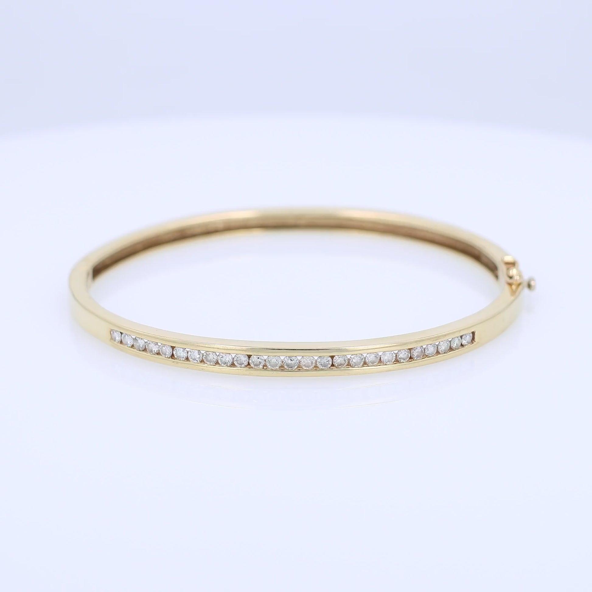 Yellow gold channel set diamond bangle bracelet on a white background