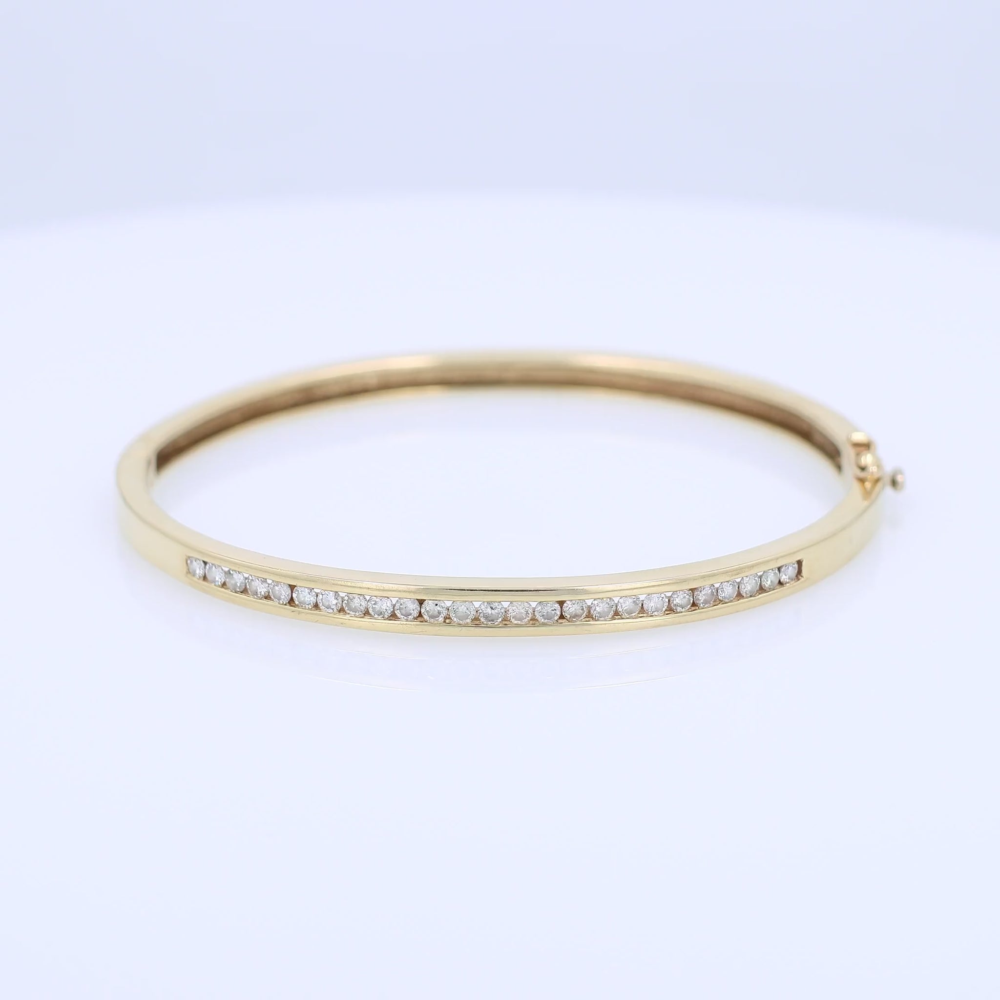 Yellow gold channel set diamond bangle bracelet on a white background