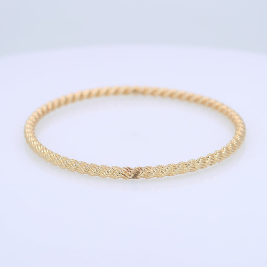 Yellow gold textured twist design 3.8mm slip on bangle bracelet on a white background