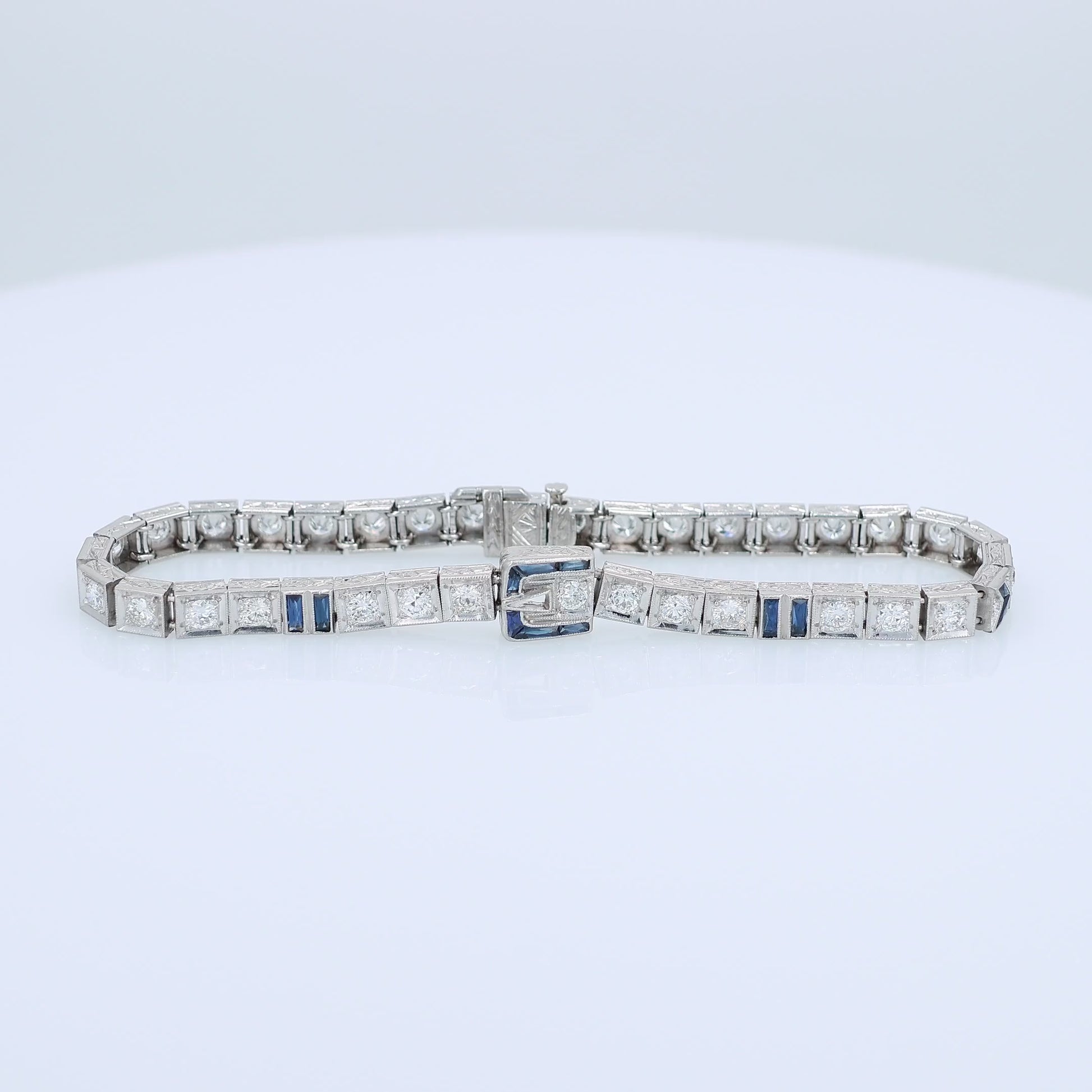 Platinum buckle design diamond and synthetic sapphire tennis bracelet on a white background
