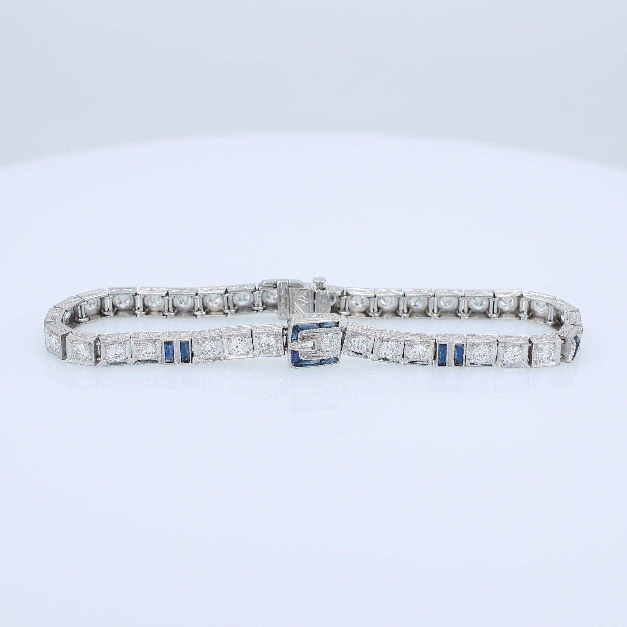 Platinum buckle design diamond and synthetic sapphire tennis bracelet on a white background