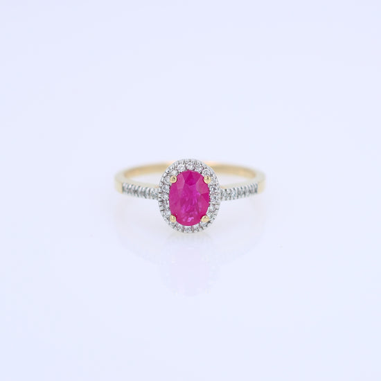 Yellow gold ruby and diamond halo ring on a white background