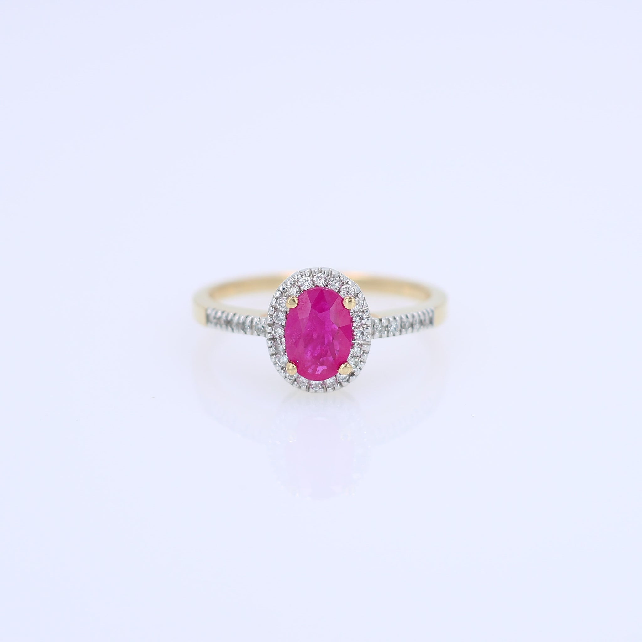 Yellow gold ruby and diamond halo ring on a white background