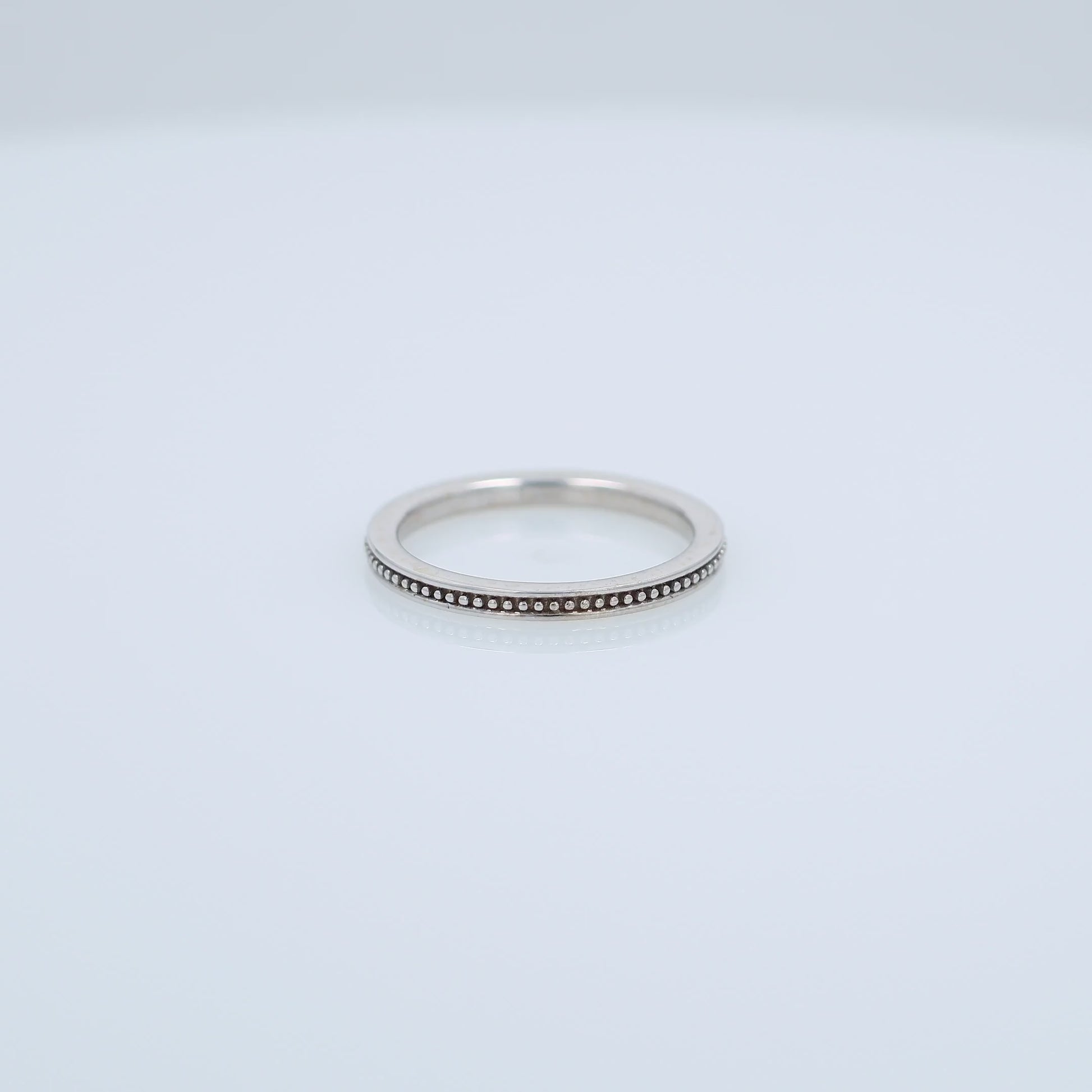 White gold ring with a milgrain center row on a white background
