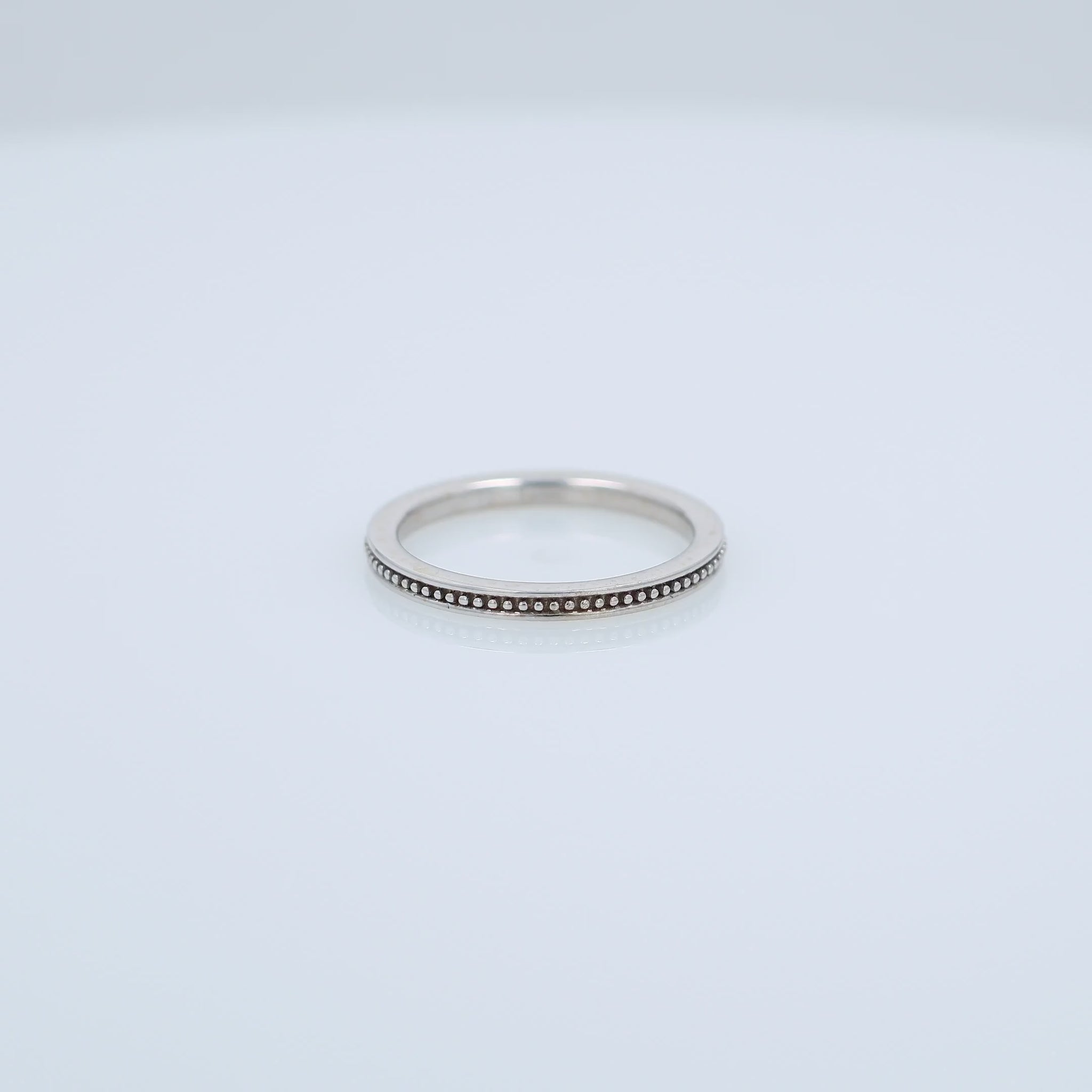 White gold ring with a milgrain center row on a white background
