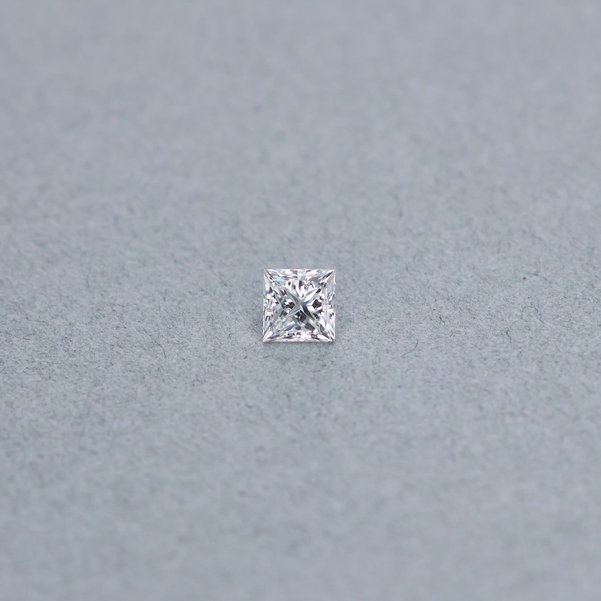 Princess cut 0.99 carat diamond graded GVS2 on a grey background